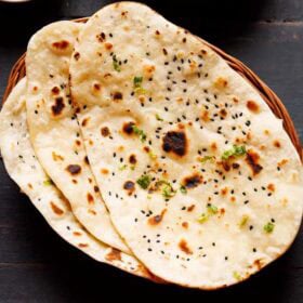 three naan stacked on a cane basket.