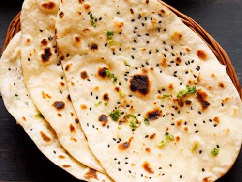three naan stacked on a cane basket.