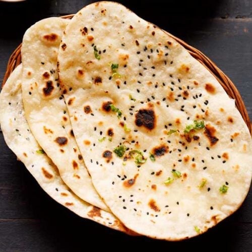 three naan stacked on a cane basket.
