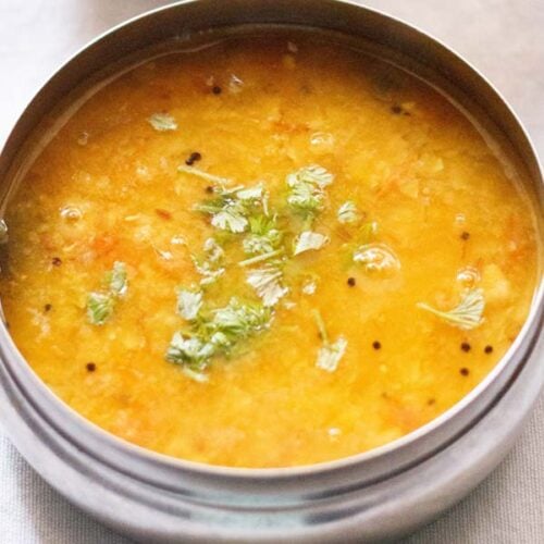tomato pappu in a steel bowl with coriander leaves in the center.
