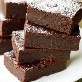 eggless brownie cut into rectangles, stacked on top of each other and served on a white plate.