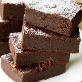 eggless brownie cut into rectangles, stacked on top of each other and served on a white plate with text layovers.