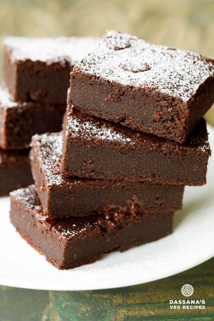 eggless brownie cut into rectangles, stacked on top of each other and served on a white plate.