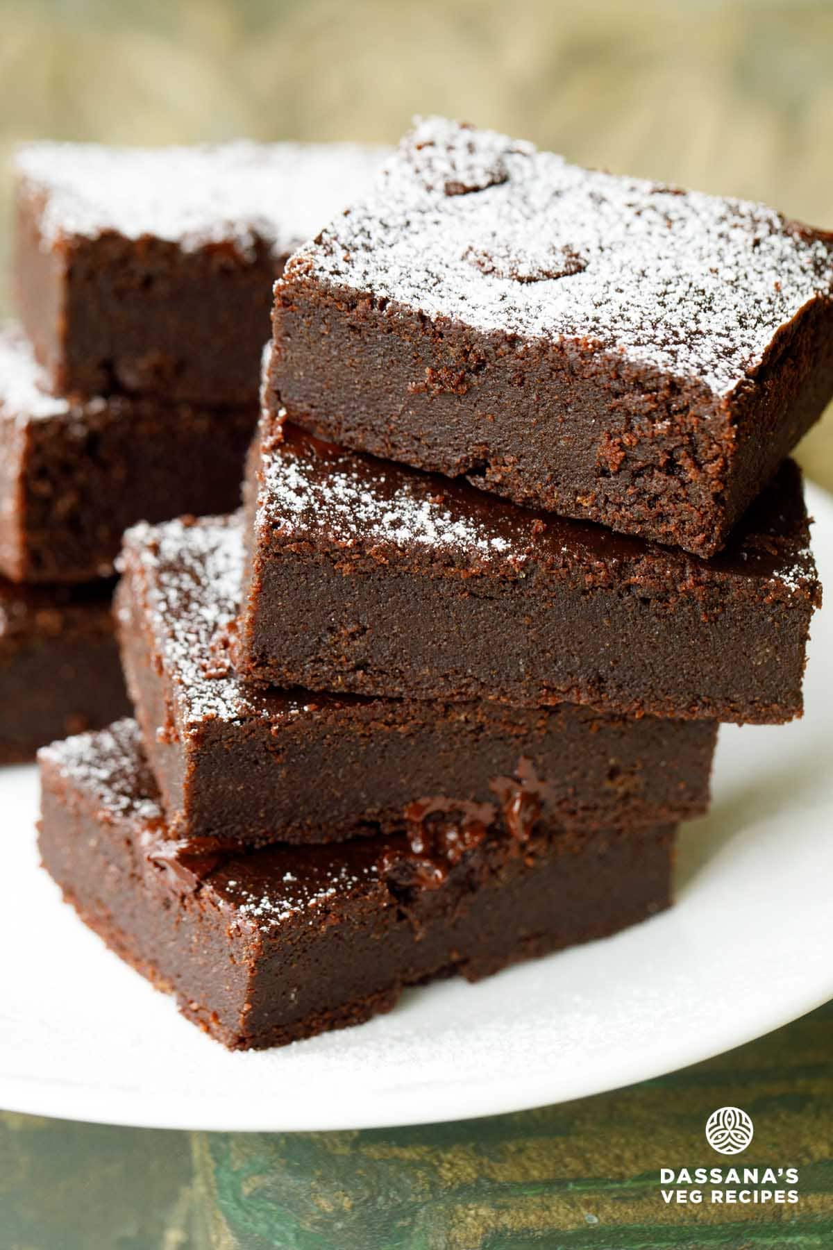eggless brownie cut into rectangles, stacked on top of each other and served on a white plate.