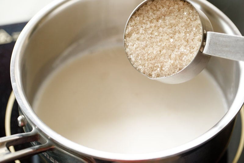 sugar being added to hot water for making cocoa solution.