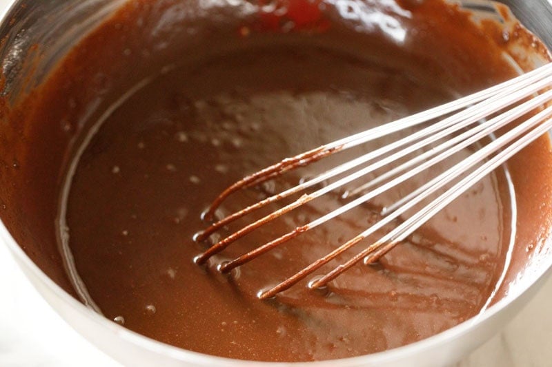 mixing ingredients with a wired whisk for eggless brownie.