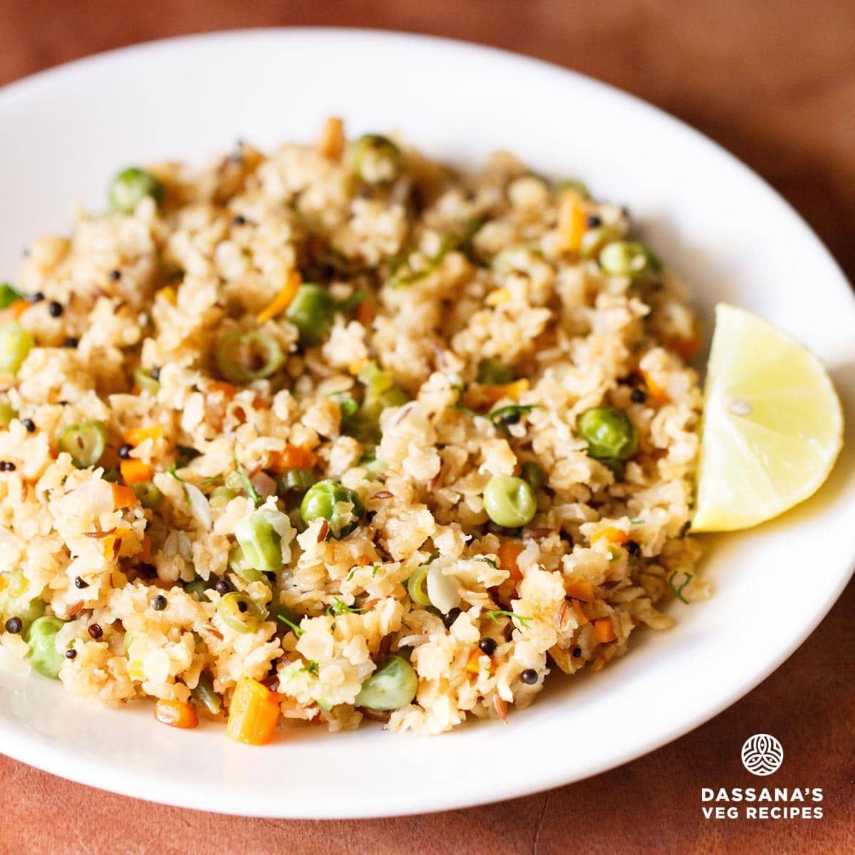 oats upma with a lemon wedge served on a white plate on a brown board.