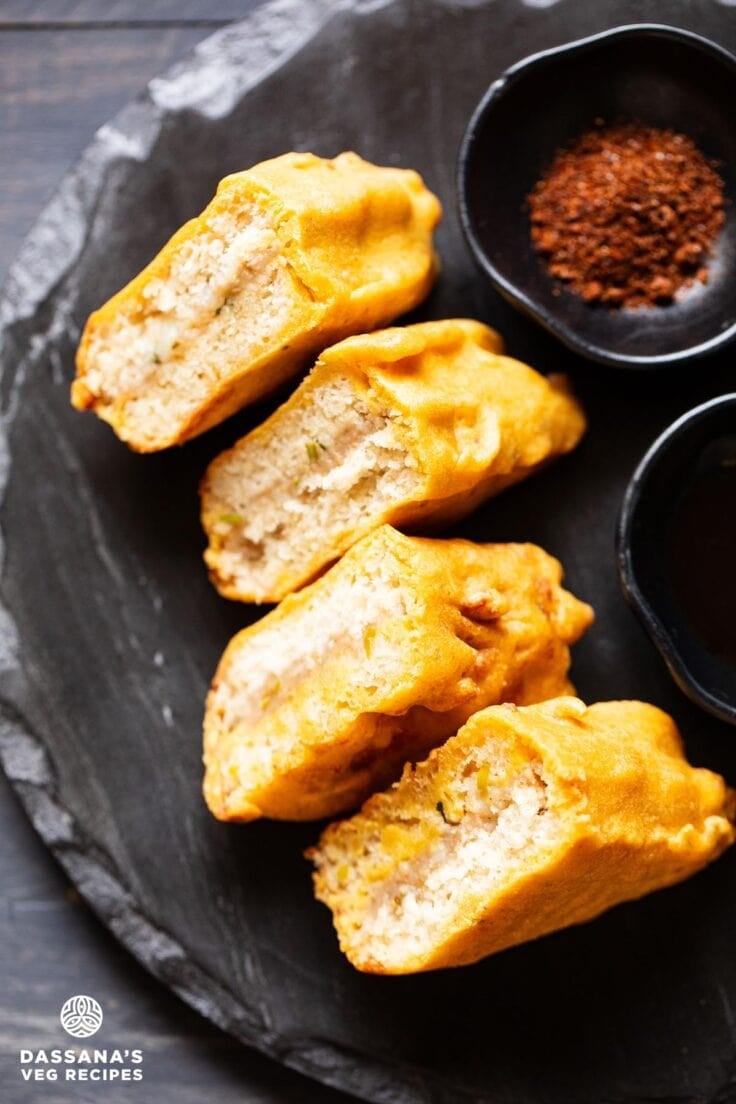 bread pakora slices on a black granite round board with chutneys by the side.
