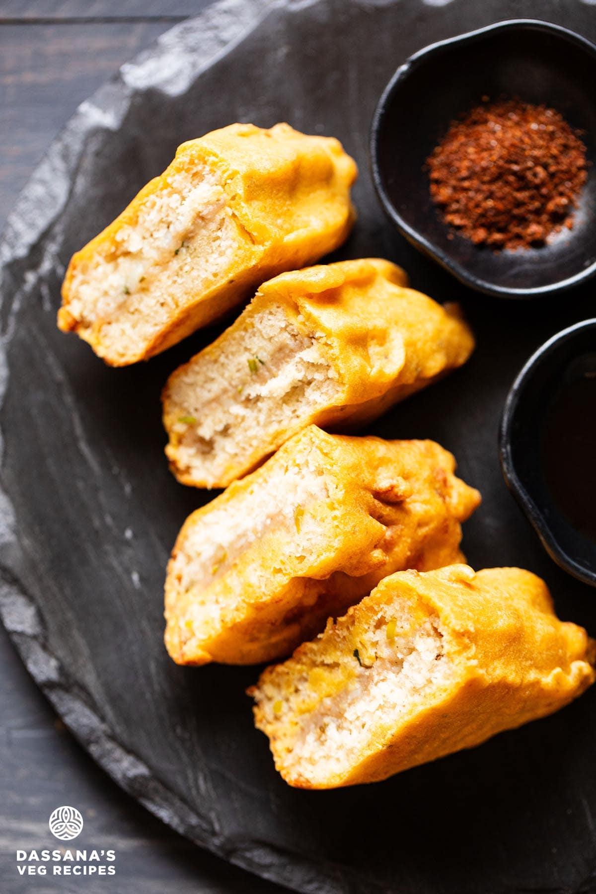 bread pakora slices on a black granite round board with chutneys by the side.