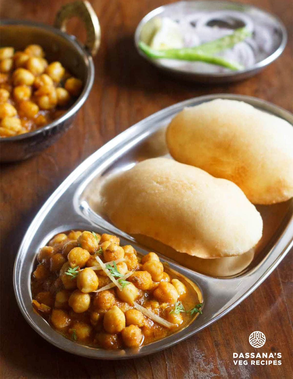 chana bhatura meal on a steel plate with sections for the curry and fried bread.