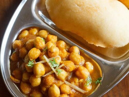 chole bhature on a plate with sections for chana curry and fried bread.