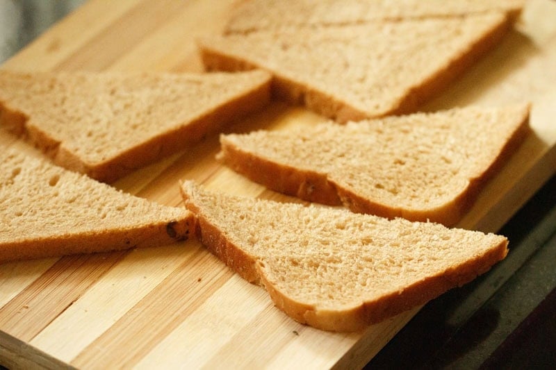 whole wheat bread sliced in triangles on a chopping board.