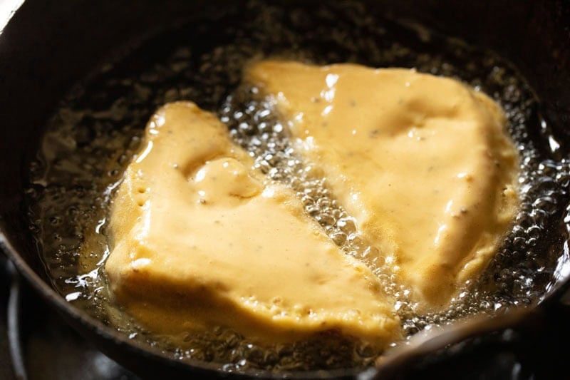 bread pakoda being fried in hot oil in a kadai.