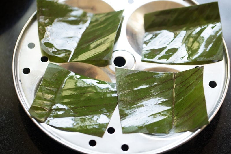 greased banana leaf pieces kept on idli stand for idiyappam recipe.