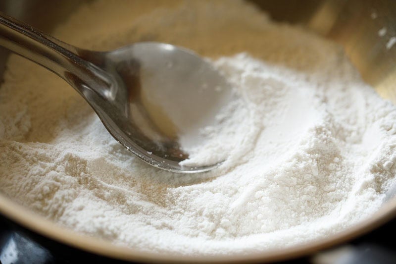 stirring rice flour in pan with a spoon.
