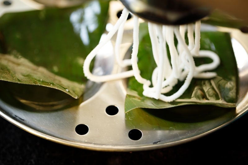 pressing idiyappam maker on idli moulds in concentric circles.
