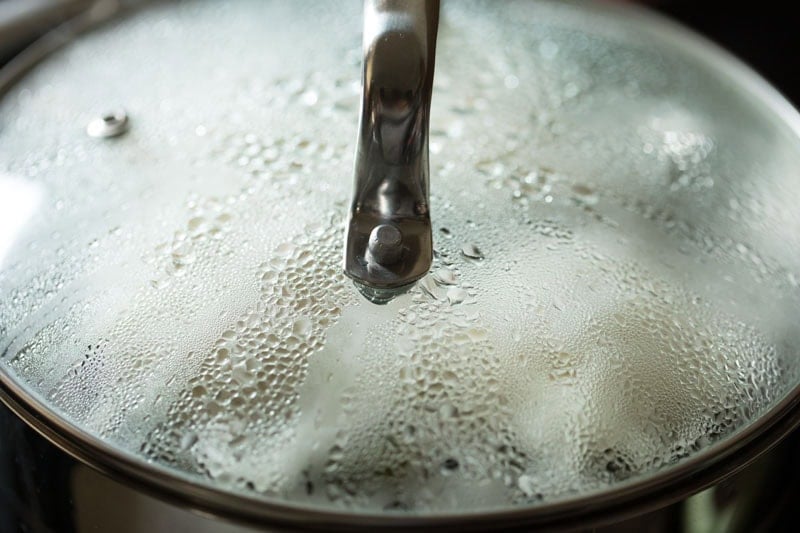  idiyappam or nool puttu steaming in a pan covered with a glass lid.