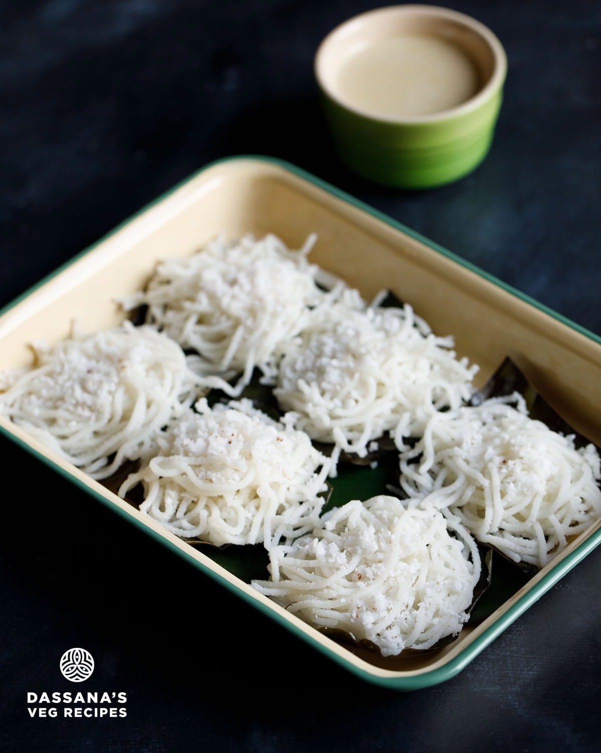 nool puttu sprinkled with grated coconut and placed on banana leaves on a tray. 