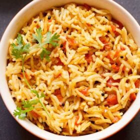 tomato rice with a coriander sprig in a bowl.