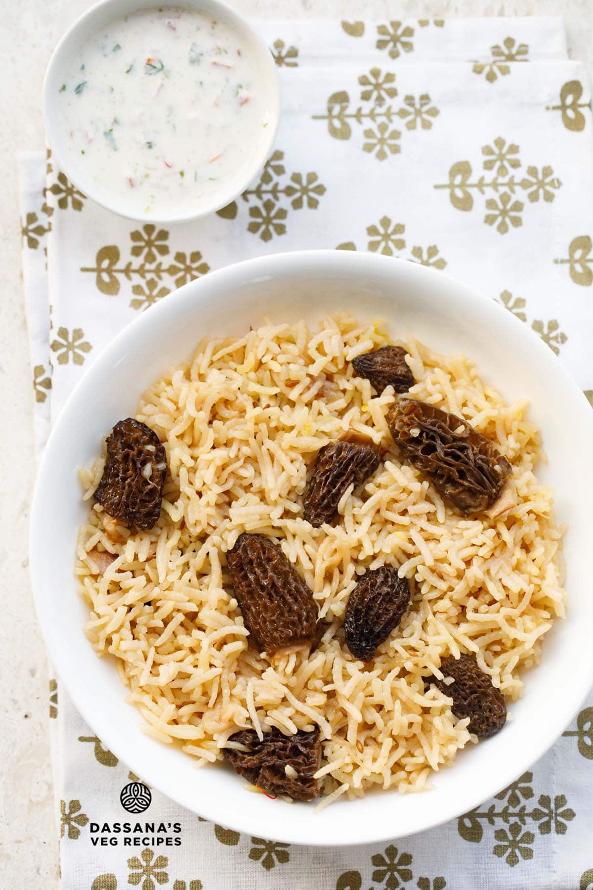 gucchi pulao (with morel mushrooms) in a white bowl on a white fabric with golden design.