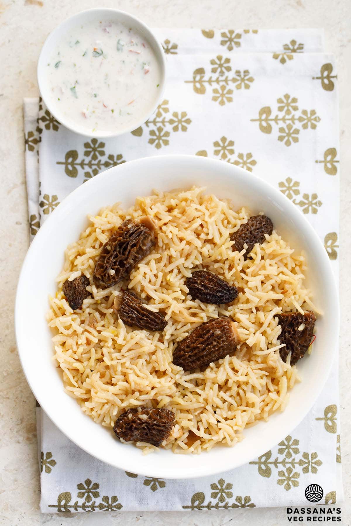 morel mushroom rice in a white bowl on a white fabric with golden design.