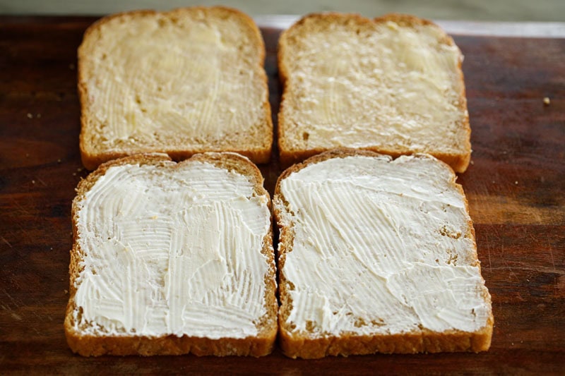 Sliced bread with butter and cream cheese spread on top.