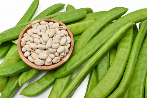 fresh sword bean pods with white beans in a small bowl.