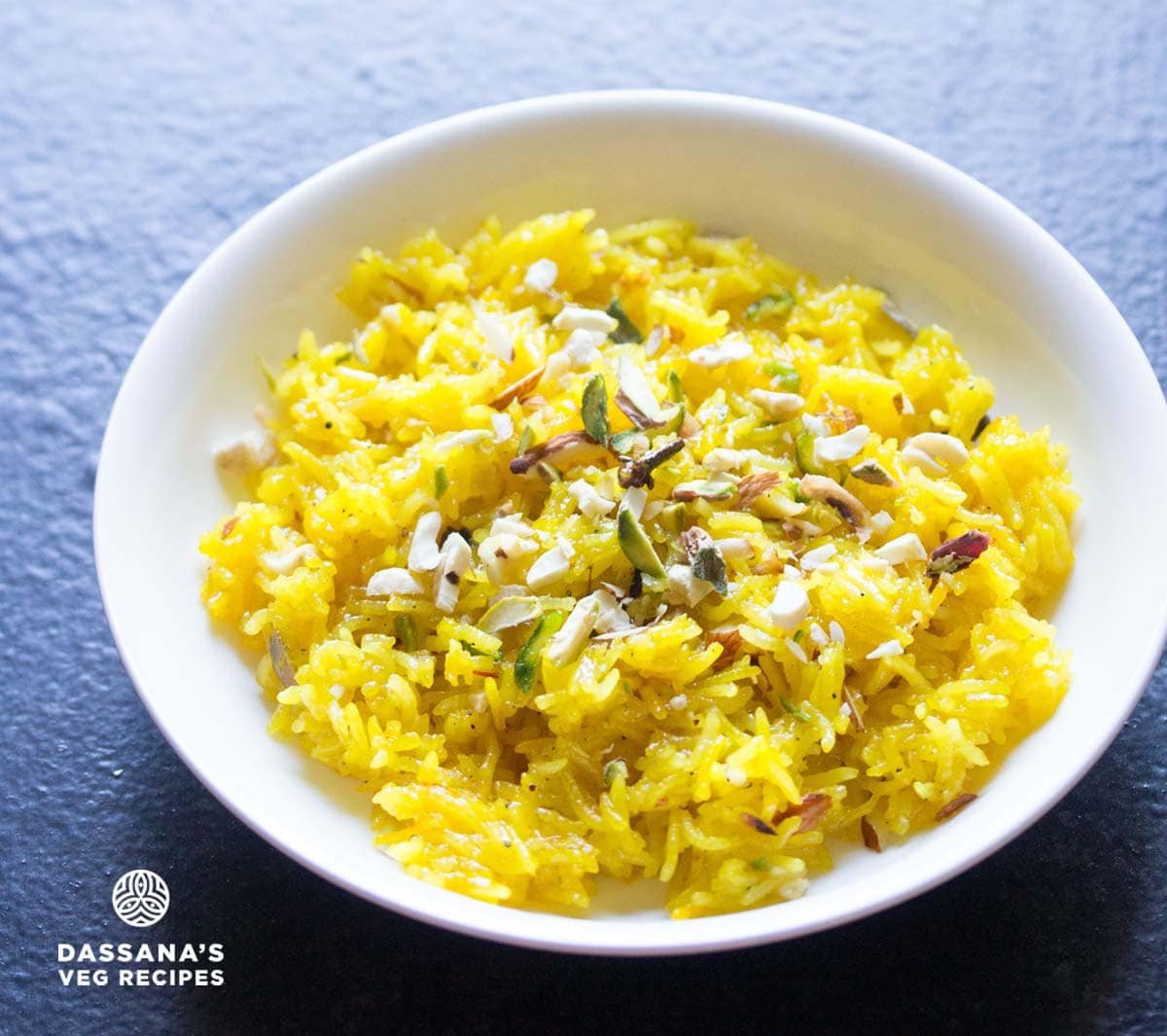 zarda pulao or sweet rice in a white bowl garnished with nuts.