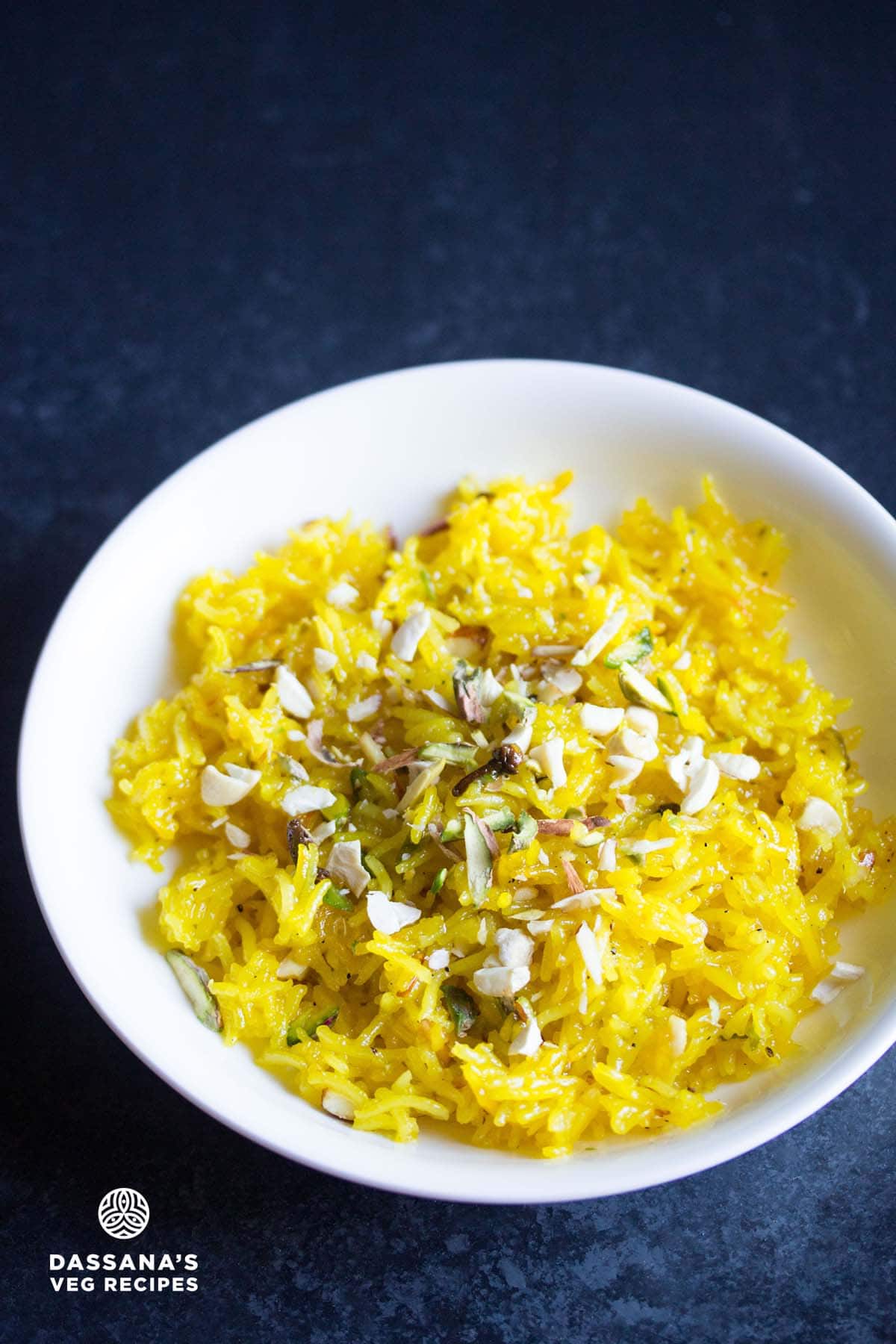 zarda pulao in a white bowl garnished with nuts.