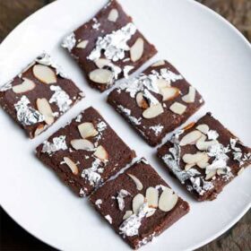 Chocolate barfi with almond toppings and silver foil.