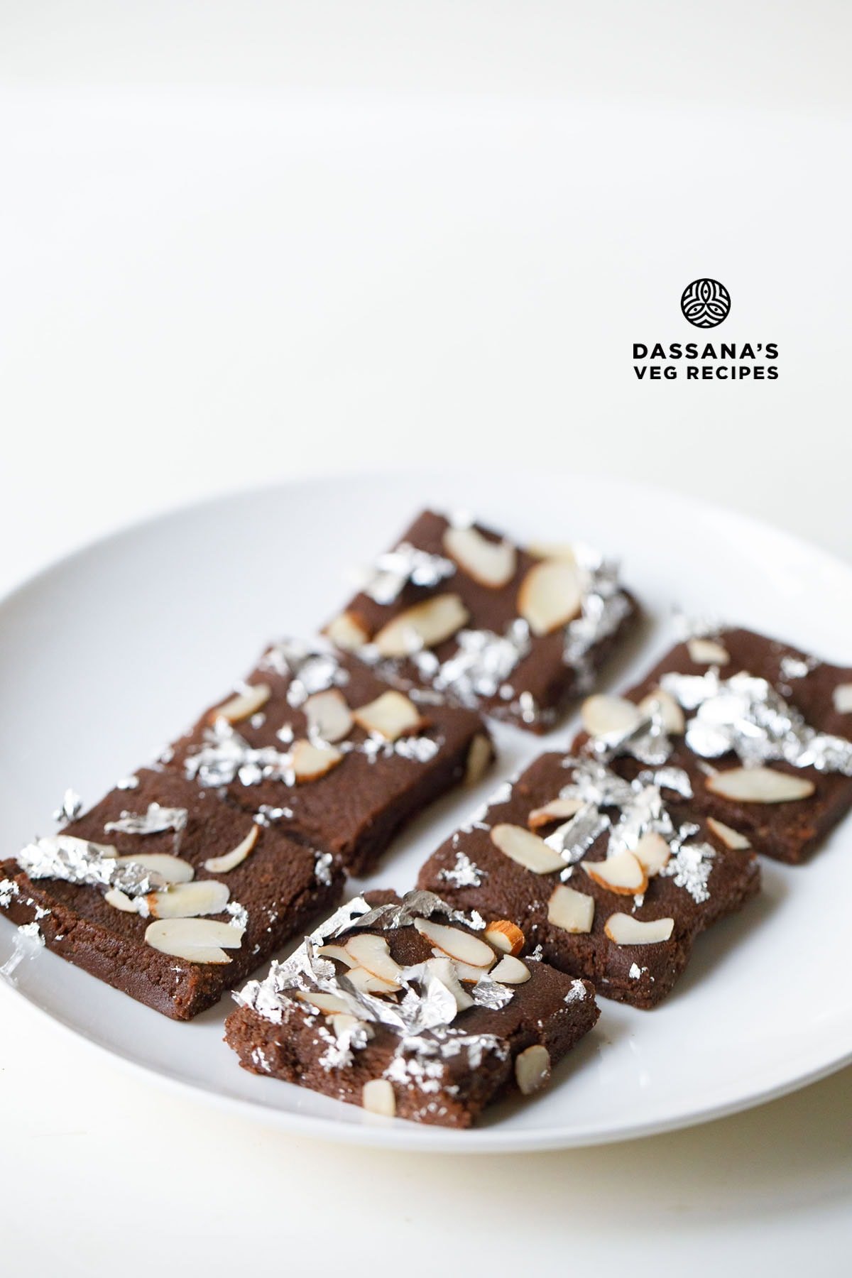 Chocolate barfi slices with almond toppings and silver foil.