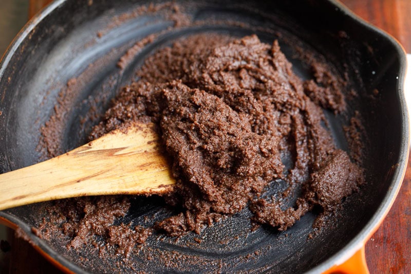 Thick chocolate mixture being stirred in skillet.
