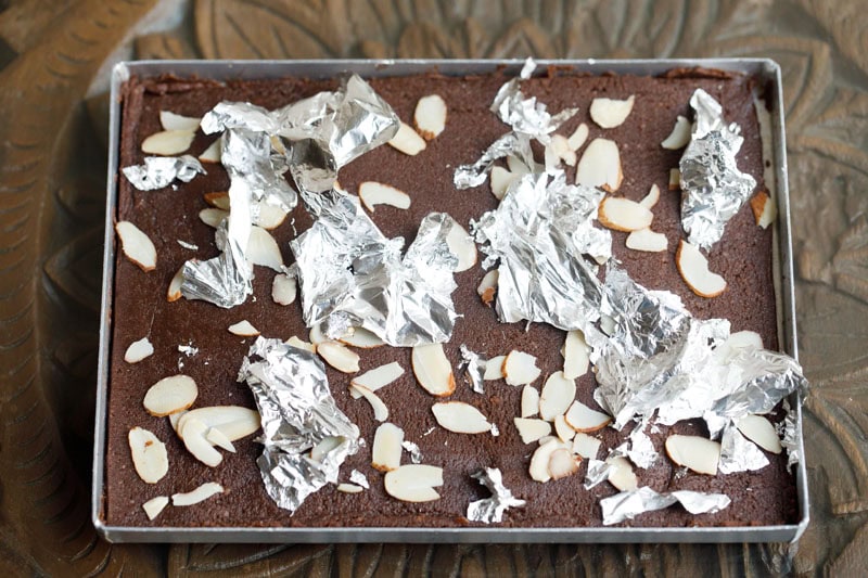 Chocolate barfi topped with almonds and silver leaf.