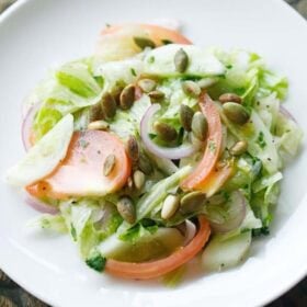 overhead shot of green salad (lettuce salad) on a white plate.