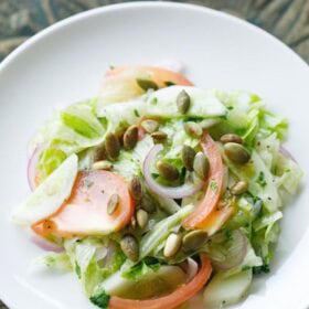 overhead shot of green salad on a white plate with text layovers.
