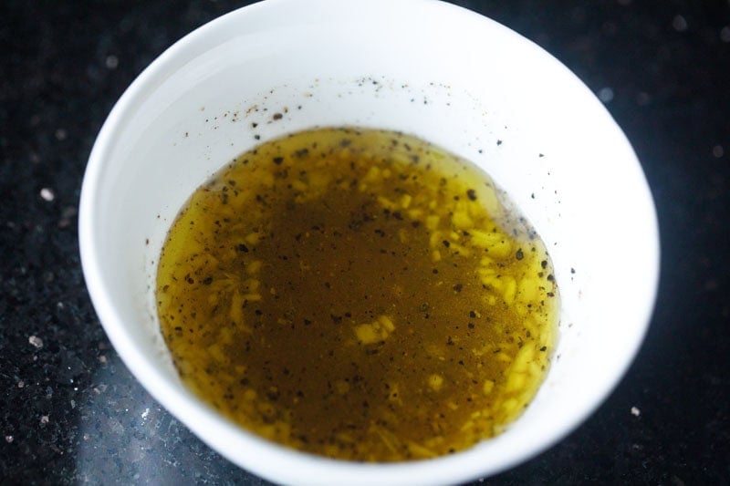 extra virgin olive oil added to lemon vinaigrette mix in bowl.