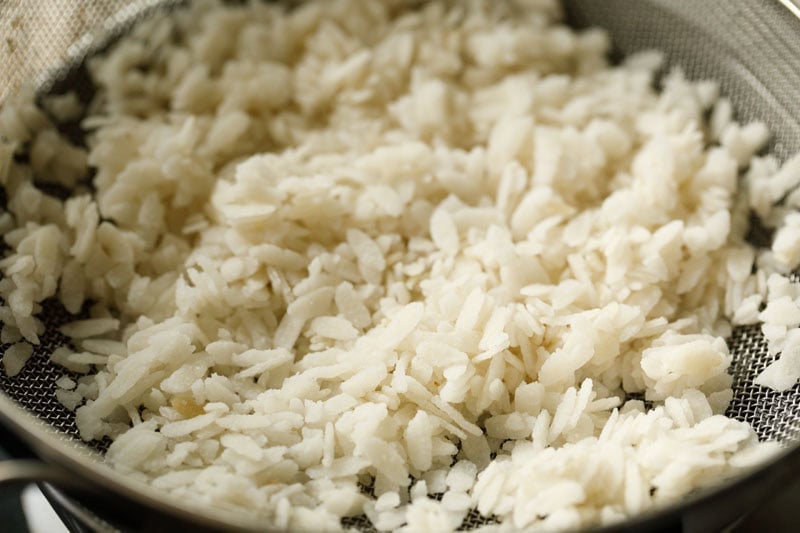 Rinsed, soft flattened rice (poha) in a strainer.