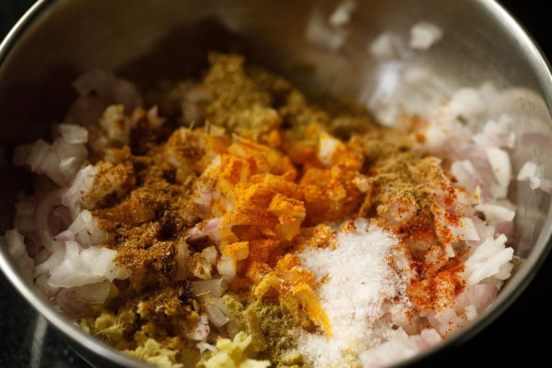 Ground spices and chopped onions in bowl with poha.