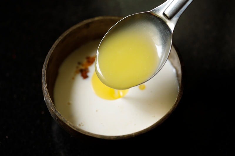 Spoon pouring ghee into bowl to make panchamrut recipe.