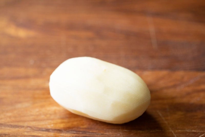 Peeled potato on wooden board.