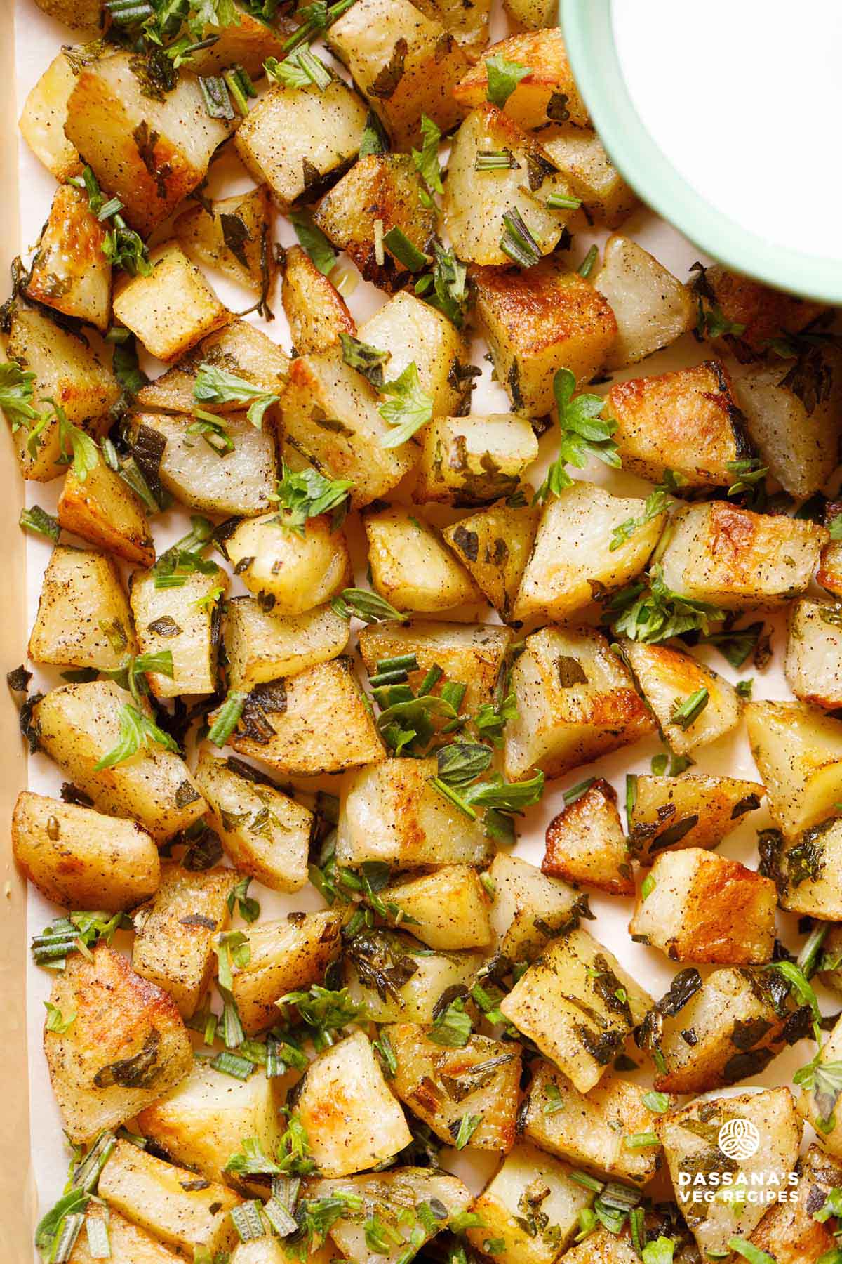 roasted potatoes on baking tray with a side of yogurt dip.