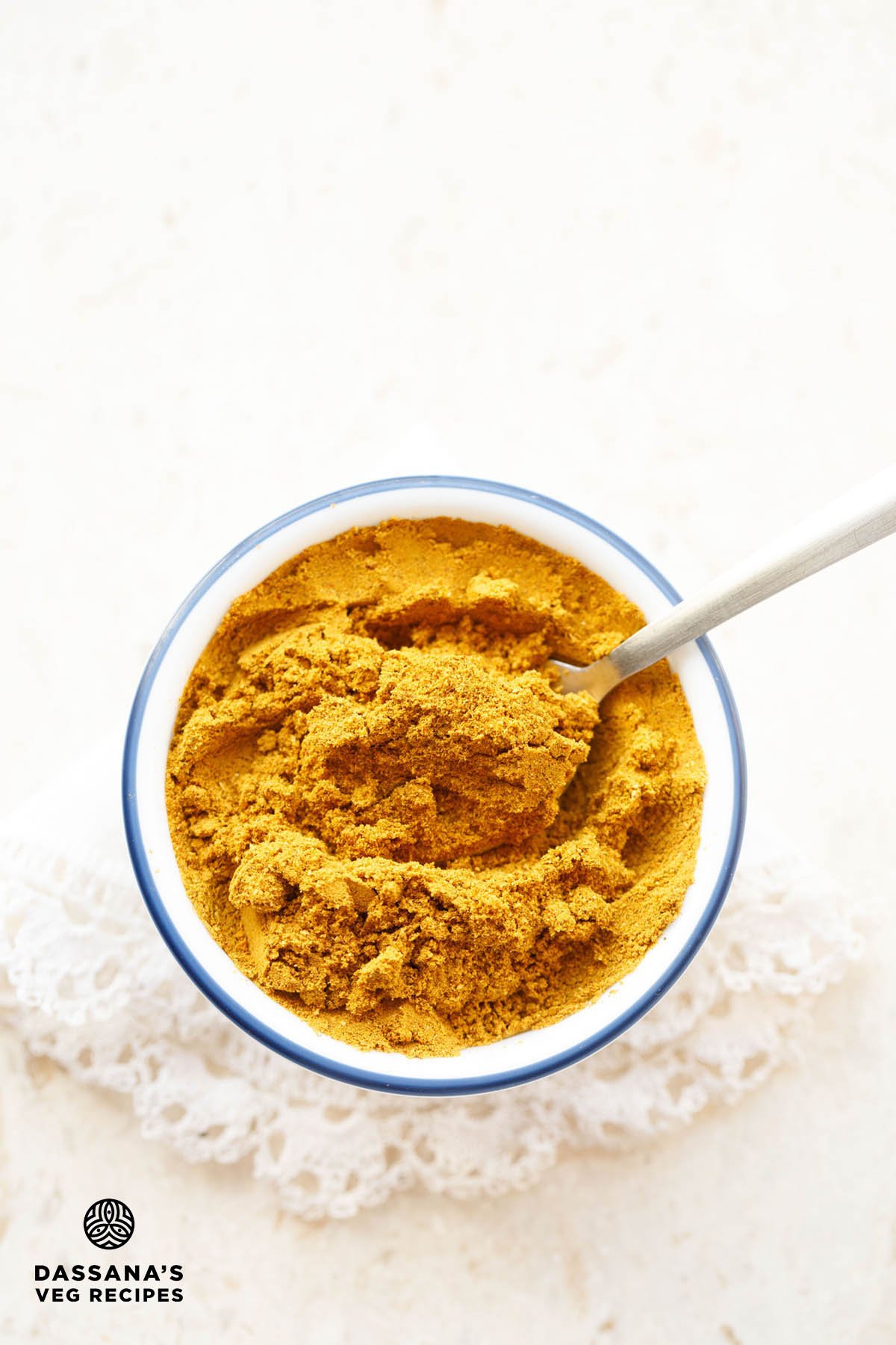 Sabji masala in a blue rimmed white bowl with spoon.