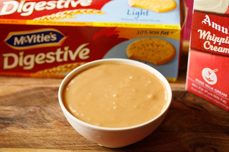 Banoffee Pie ingredients – digestive biscuits, whipping cream pack and homemade dulce de leche in a bowl.