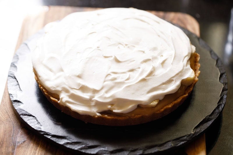 Whipped cream spread over the banana slices to make banoffee pie.