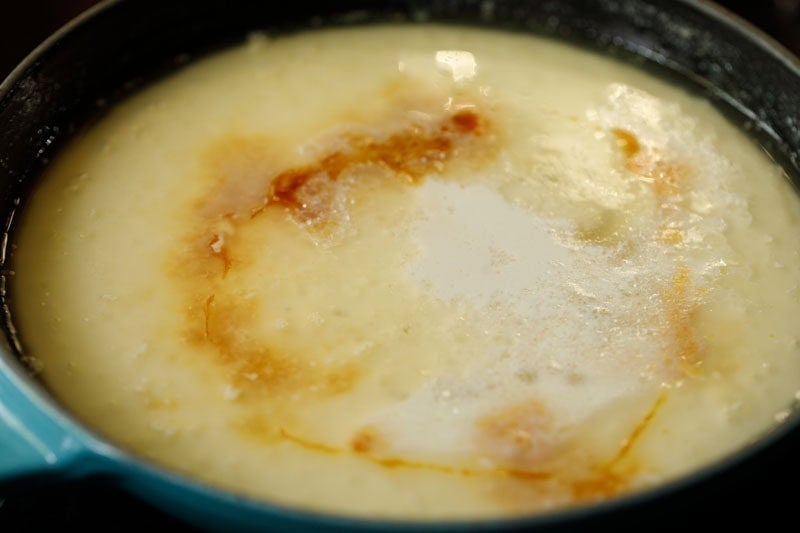 Condensed milk, vanilla and milk on melted butter in skillet.