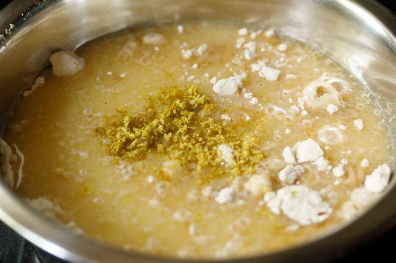 Liquid mixture on the flour mixture in a bowl with lemon zest.