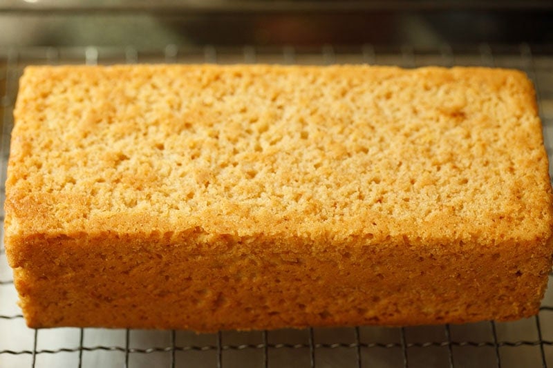 Freshly baked golden lemon loaf cake on wired tray.