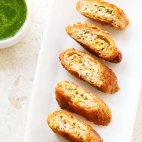 Crispy dahi ke sholay with yogurt or curd stuffing on a white platter with green chutney.