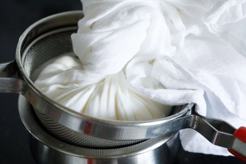Straining yogurt in a cloth bundle.