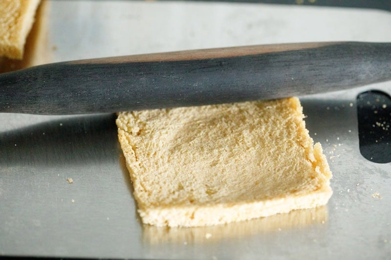 Rolling pin flattening slice of bread.